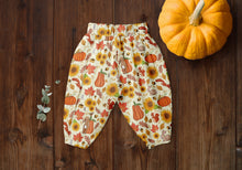 Load image into Gallery viewer, Orange and yellow trousers made from Autumn fabric. Showing pumpkins, sunflowers, bunnies, squirrels, and birds.
