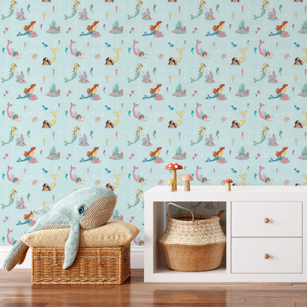 Lifestyle image of a baby's nursery with Belle and Boo's blue mermaid design on the wallpaper. 